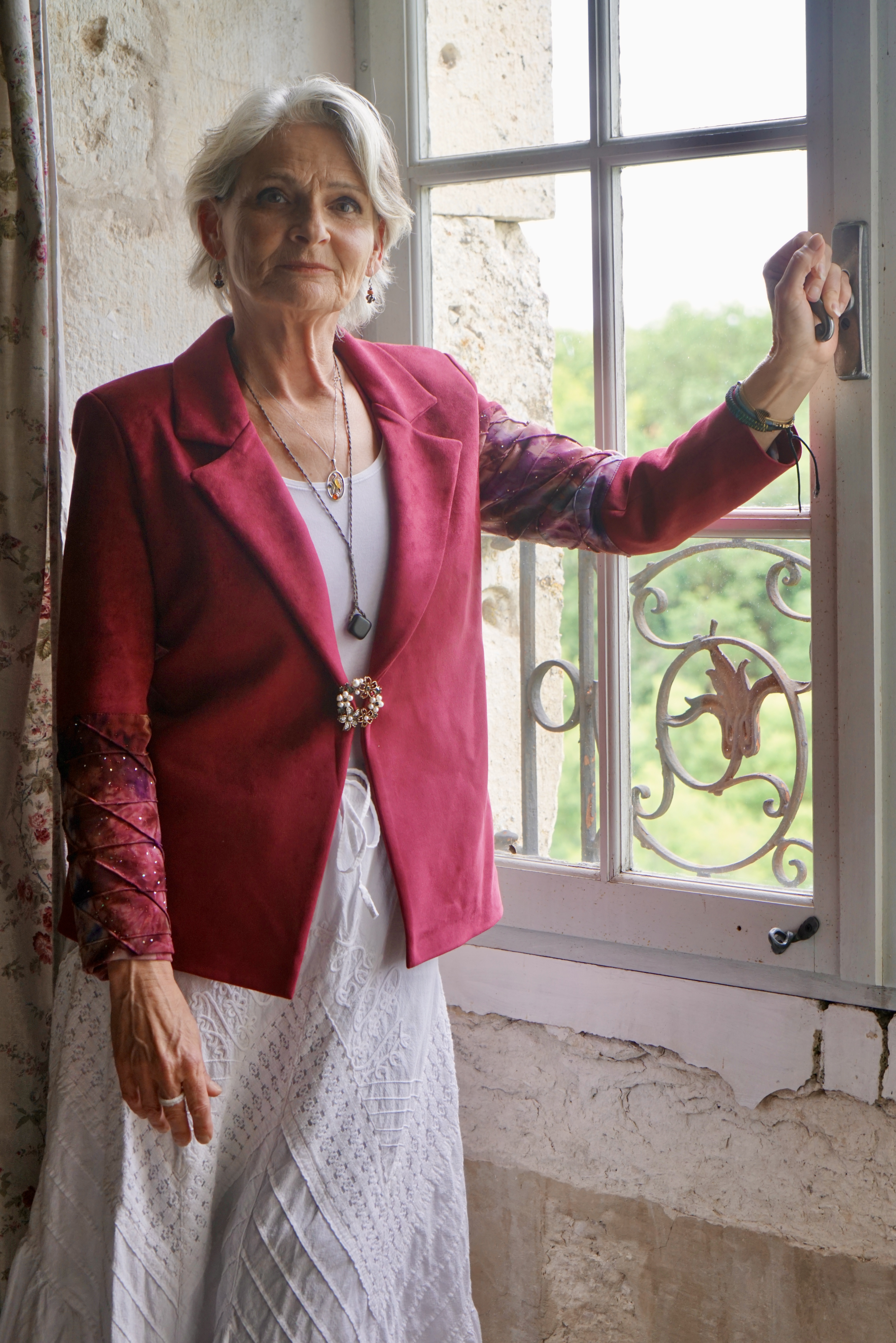 Gros plan sur une veste en velours rouge et une jupe longue blanche